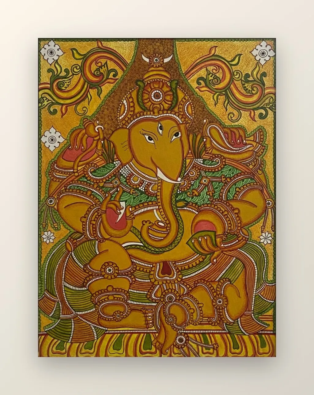 Lord Ganapathy seated in benediction, framed by scrolling foliage and ornament.